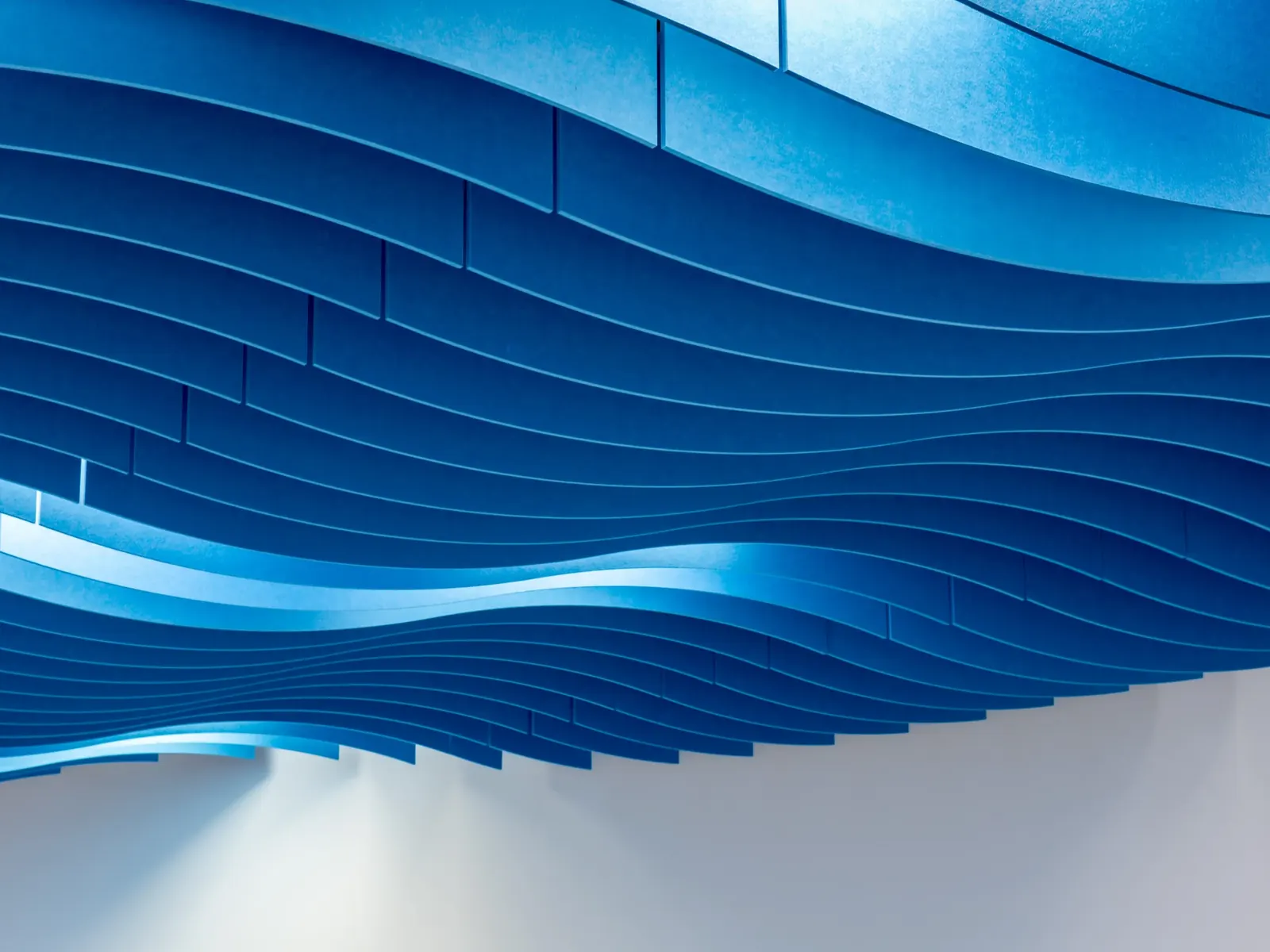 Ecocero Baffle, composición ondulada de bafles azules en un techo