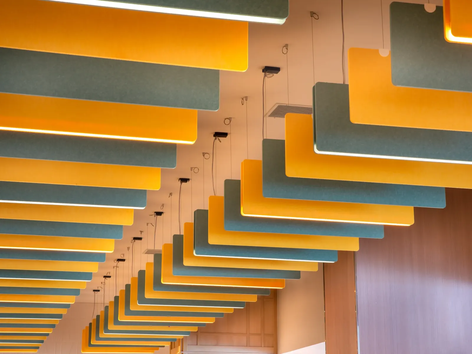 Ecocero Baffle, composición de bafles en tonos naranja y verde sobre un techo de madera
